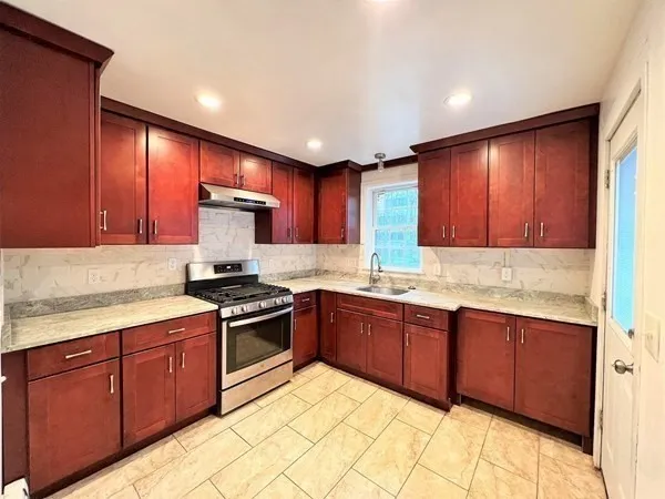 a kitchen with stainless steel appliances granite countertop wooden cabinets a stove top oven a sink and dishwasher with wooden floor