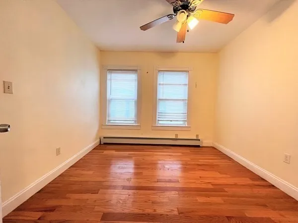 a view of an empty room with window and wooden floor
