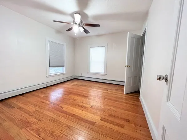 a view of empty room with wooden floor and fan