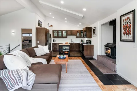 a living room with furniture kitchen view and a wooden floor