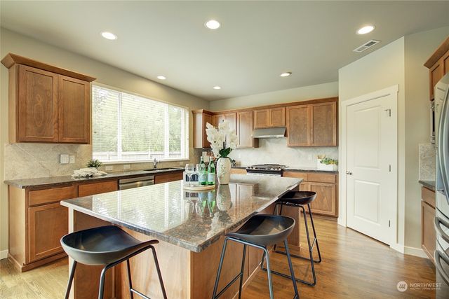 a kitchen with stainless steel appliances granite countertop table chairs sink and cabinets