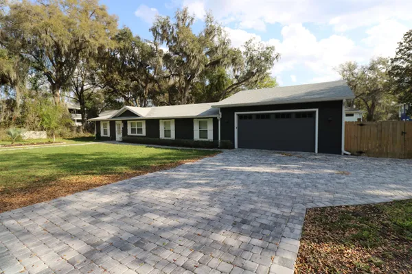 a view of a house with a yard and large tree
