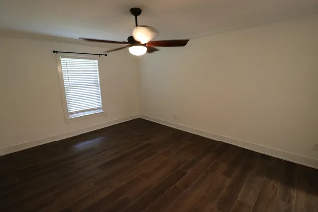 an empty room with wooden floor fan and windows