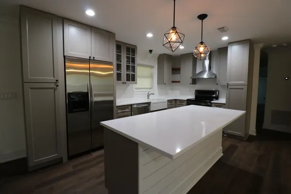 a large kitchen with stainless steel appliances a refrigerator and a wooden floor