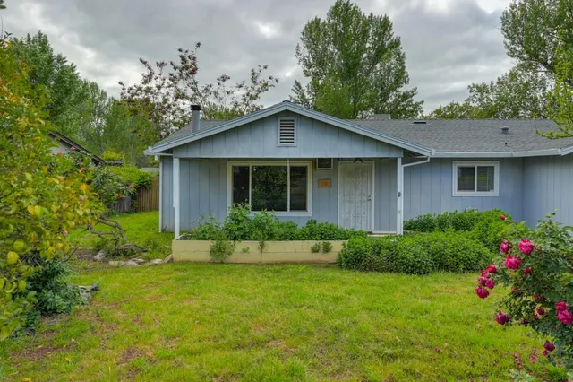 a front view of a house with a yard and potted plants