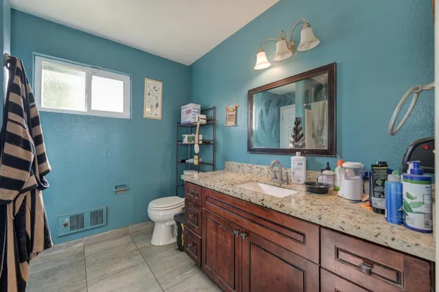 a bathroom with a granite countertop sink a mirror and a toilet