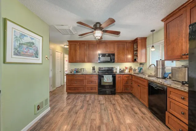 a kitchen with stainless steel appliances granite countertop a stove cabinets and wooden floor