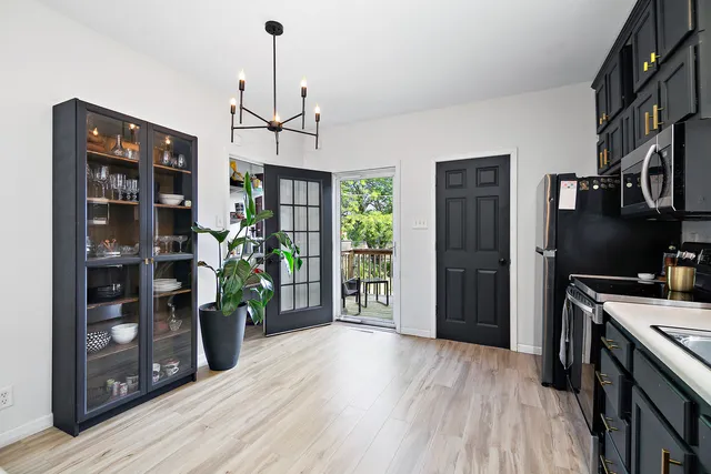 a kitchen view with stainless steel appliances granite countertop a refrigerator oven a stove and a dining table with wooden floor