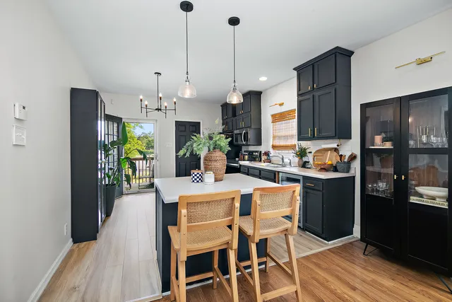 a kitchen with stainless steel appliances kitchen island granite countertop a refrigerator a stove a sink a dining table and chairs with wooden floor