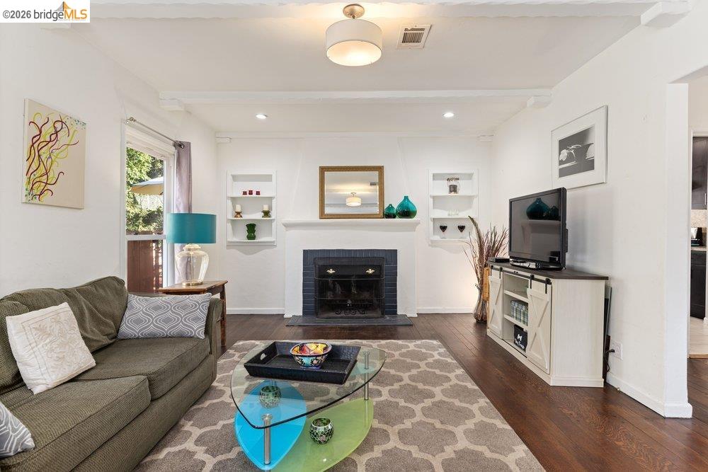 9600 Golf Links Road Oakland, CA 94605 - Photo 14 of 47 Living room featuring beamed ceiling, dark wood-type flooring, a fireplace, built in shelves, and recessed lighting