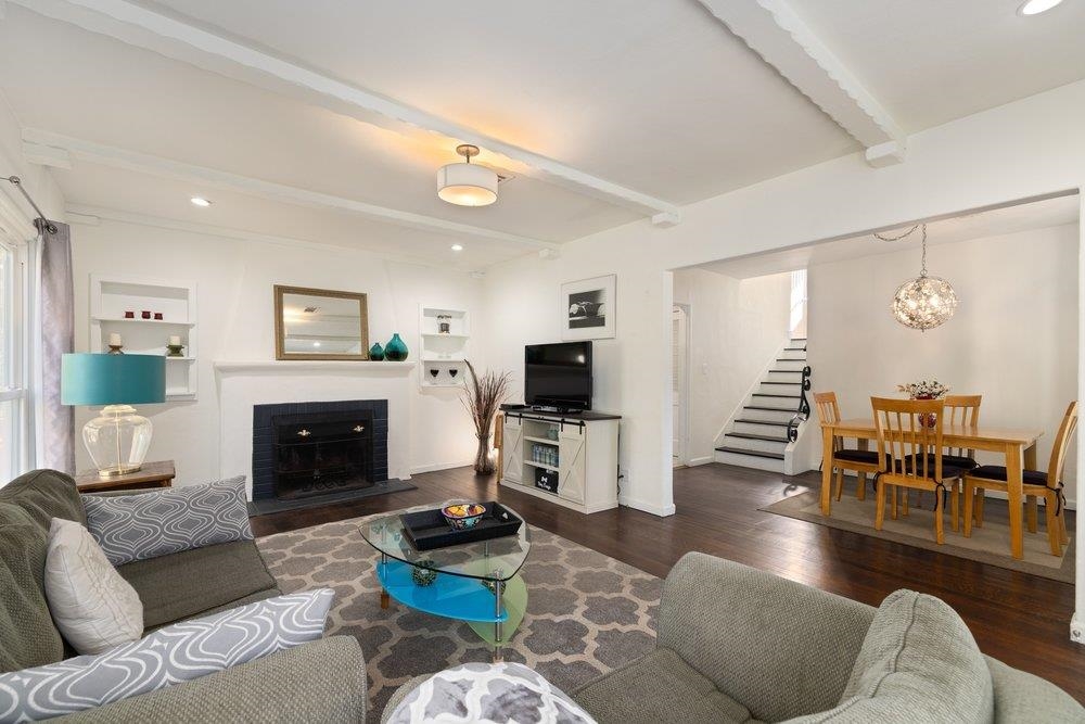 9600 Golf Links Road Oakland, CA 94605 - Photo 16 of 47 Living area featuring beamed ceiling, dark wood-style floors, a fireplace, a chandelier, and stairway