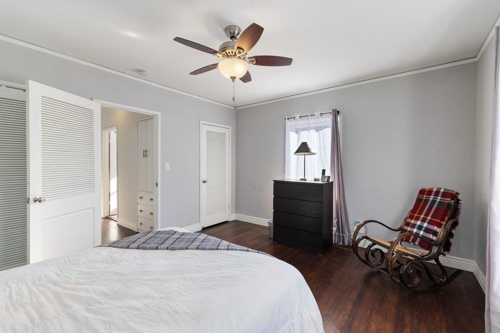 9600 Golf Links Road Oakland, CA 94605 - Photo 24 of 47 Bedroom with dark wood-type flooring, multiple closets, walk-in closet, ornamental molding, and a ceiling fan