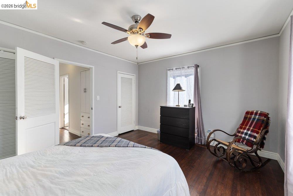 9600 Golf Links Road Oakland, CA 94605 - Photo 24 of 47 Bedroom with dark wood-type flooring, multiple closets, walk-in closet, ornamental molding, and a ceiling fan