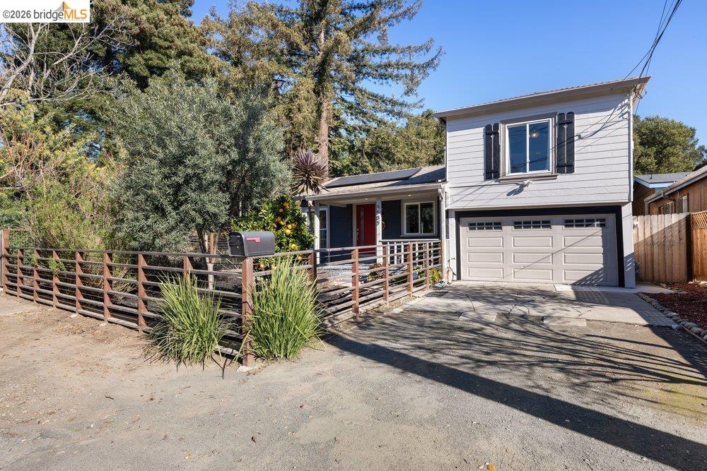 9600 Golf Links Road Oakland, CA 94605 - Photo 3 of 47 Tri-level home with roof mounted solar panels, driveway, an attached garage, and covered porch