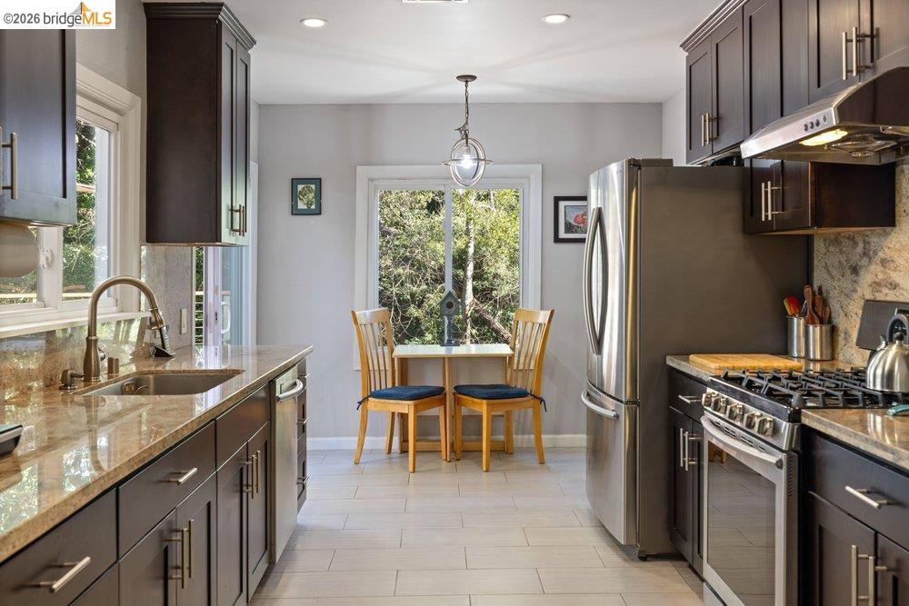 9600 Golf Links Road Oakland, CA 94605 - Photo 32 of 47 Kitchen with dark brown cabinets, stainless steel appliances, light stone counters, under cabinet range hood, and recessed lighting