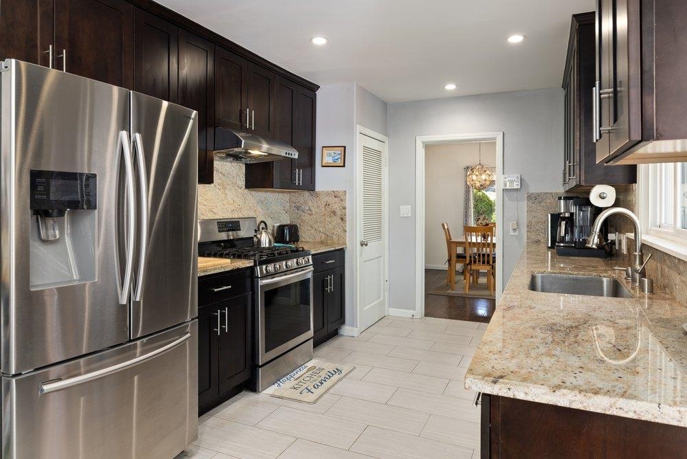 9600 Golf Links Road Oakland, CA 94605 - Photo 37 of 47 Kitchen with appliances with stainless steel finishes, light stone counters, under cabinet range hood, dark brown cabinets, and recessed lighting