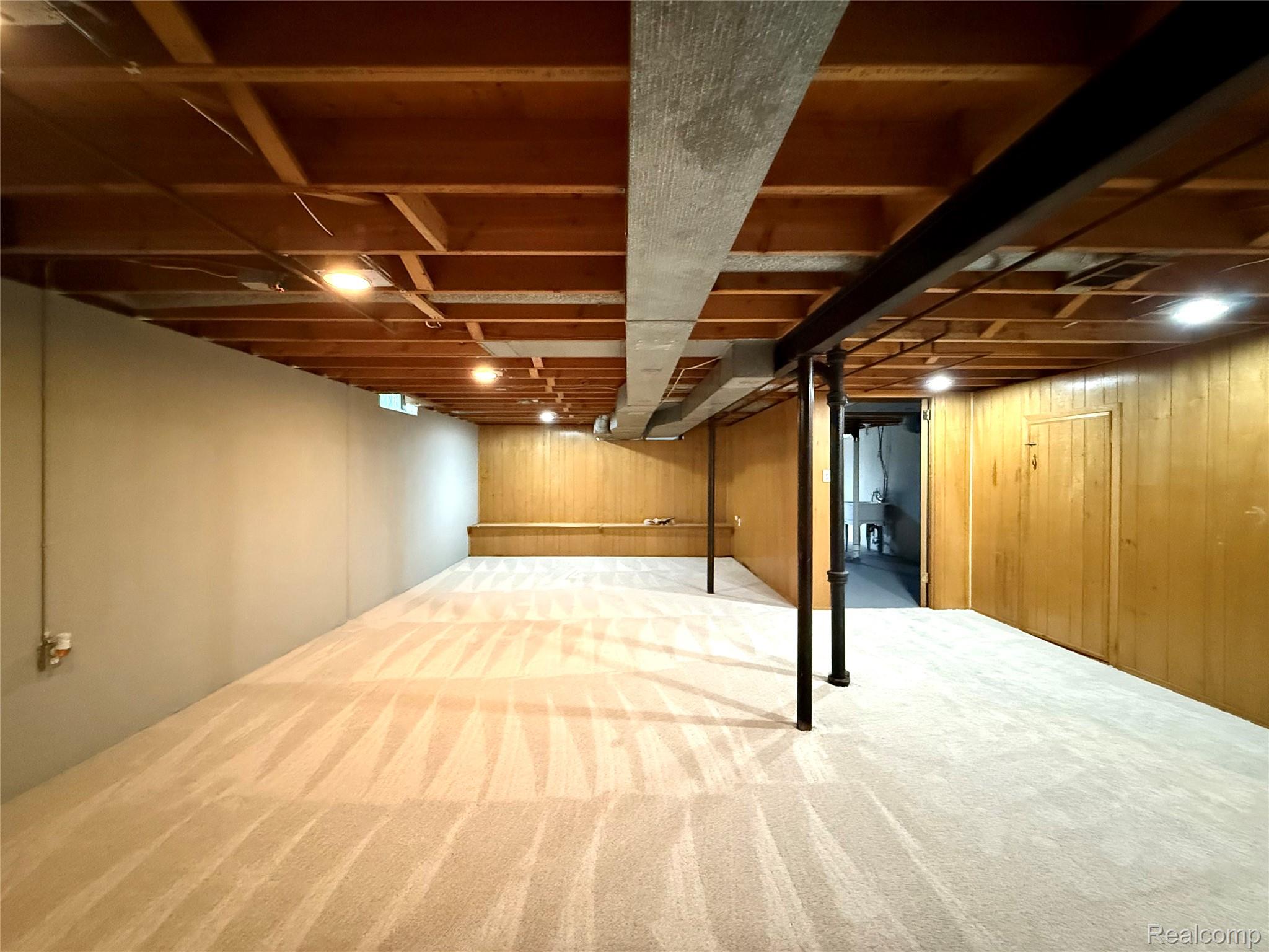 39909 Lynn Street Canton, MI 48187 - Photo 32 of 45 Spacious lower level featuring light-toned carpeting, wood-paneled walls, exposed ceiling joists with recessed lighting, and structural support columns