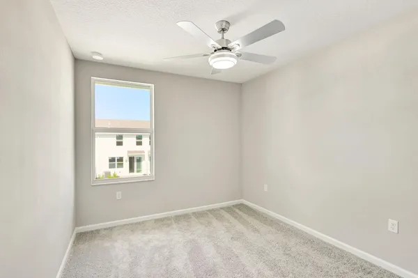 an empty room with windows and fan
