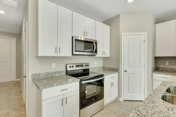 a kitchen with granite countertop white cabinets and white appliances