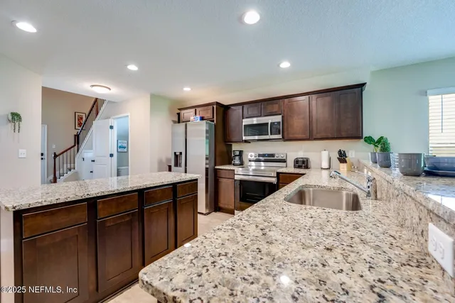 a kitchen with stainless steel appliances granite countertop a sink stove and refrigerator