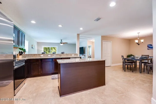 a kitchen with stainless steel appliances kitchen island granite countertop a refrigerator a stove a sink a dining table and chairs