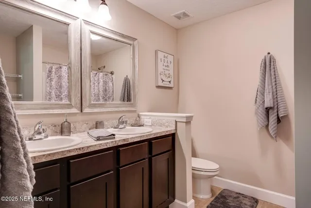 a bathroom with a granite countertop sink toilet and mirror