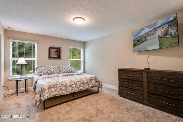 a bedroom with a large bed and a flat tv screen on dresser