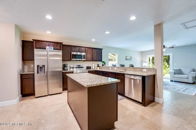 a kitchen with stainless steel appliances kitchen island granite countertop a refrigerator a sink a stove a microwave and island