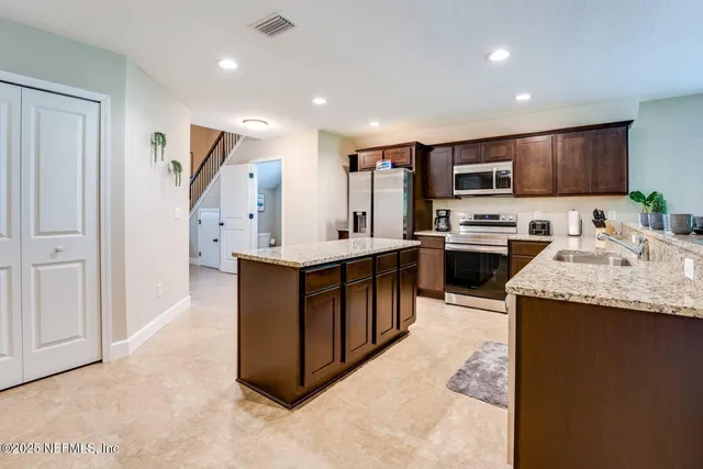 a kitchen with stainless steel appliances granite countertop a stove top oven a sink a refrigerator and a oven