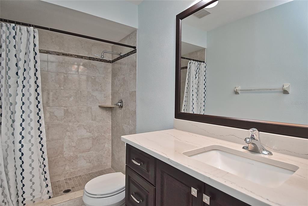 4058 Center Pointe Place, Unit 28A Sarasota, FL 34233 - Photo 11 of 24 a bathroom with a granite countertop sink toilet a mirror a vanity and shower