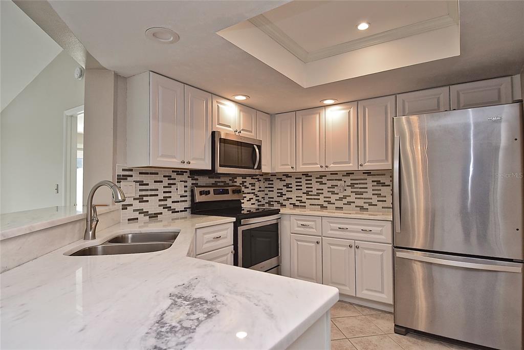 4058 Center Pointe Place, Unit 28A Sarasota, FL 34233 - Photo 6 of 24 a kitchen with white cabinets and stainless steel appliances