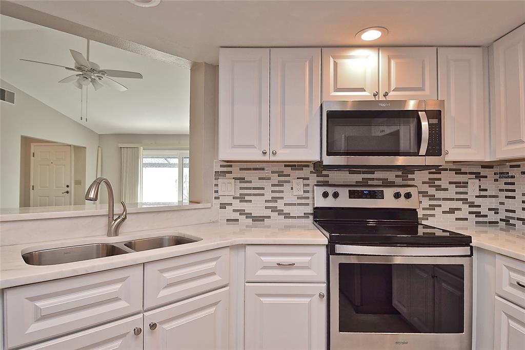 4058 Center Pointe Place, Unit 28A Sarasota, FL 34233 - Photo 7 of 24 a kitchen with cabinets stainless steel appliances a sink and a microwave
