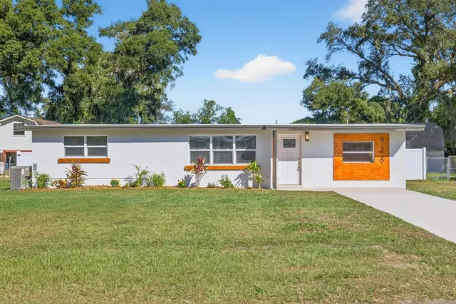 a view of a house with a yard and a tree
