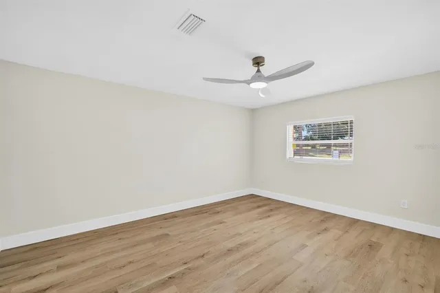 an empty room with wooden floor and ceiling fan