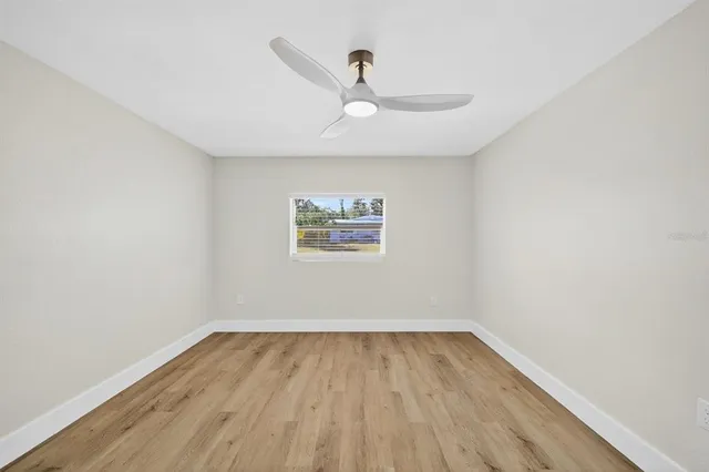 a view of an empty room with wooden floor and a window