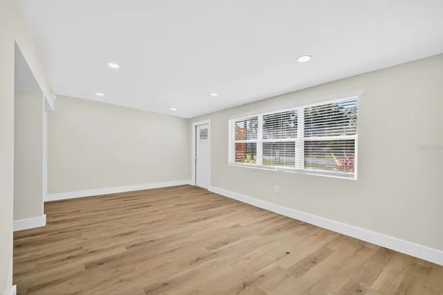 a view of an empty room with wooden floor and a window
