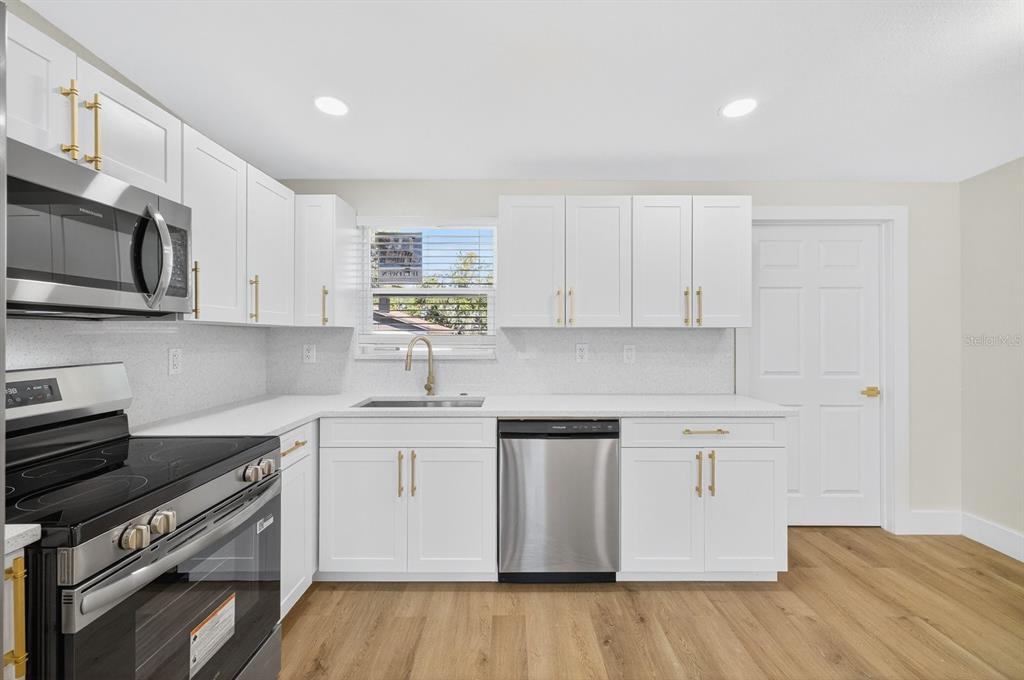 928 Valmar Street Brandon, FL 33511 - Photo 8 of 35 a kitchen with stainless steel appliances granite countertop a stove top oven a sink dishwasher and white cabinets with wooden floor