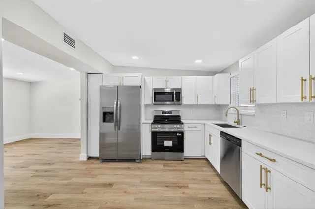 a kitchen with stainless steel appliances granite countertop a refrigerator and a stove top oven