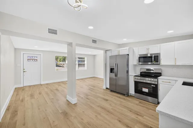 a kitchen with granite countertop a refrigerator and a stove top oven