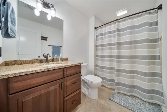 a bathroom with a granite countertop sink a toilet a mirror and shower