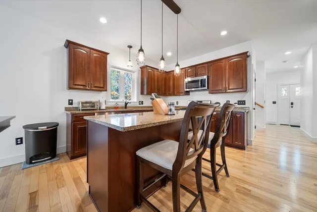 a kitchen with stainless steel appliances wooden floor dining table and chairs