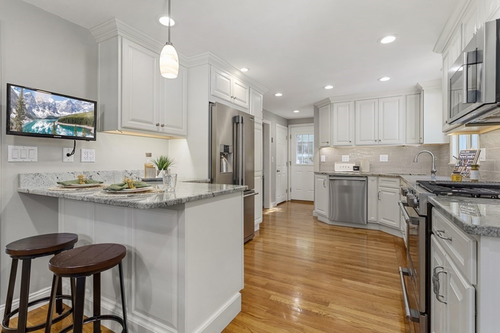 25 Oak Street Reading, MA 01867 - Photo 12 of 42 a kitchen with stainless steel appliances granite countertop a sink counter space and a refrigerator