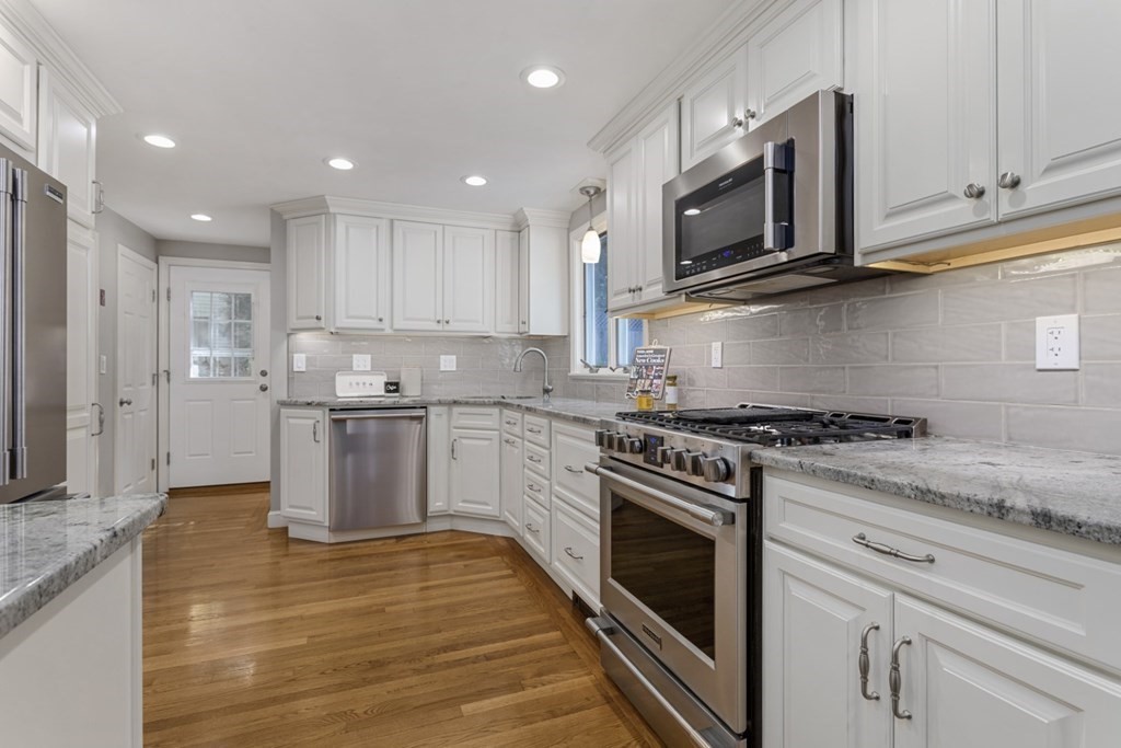 25 Oak Street Reading, MA 01867 - Photo 13 of 42 a kitchen with stainless steel appliances granite countertop a stove a sink and a microwave
