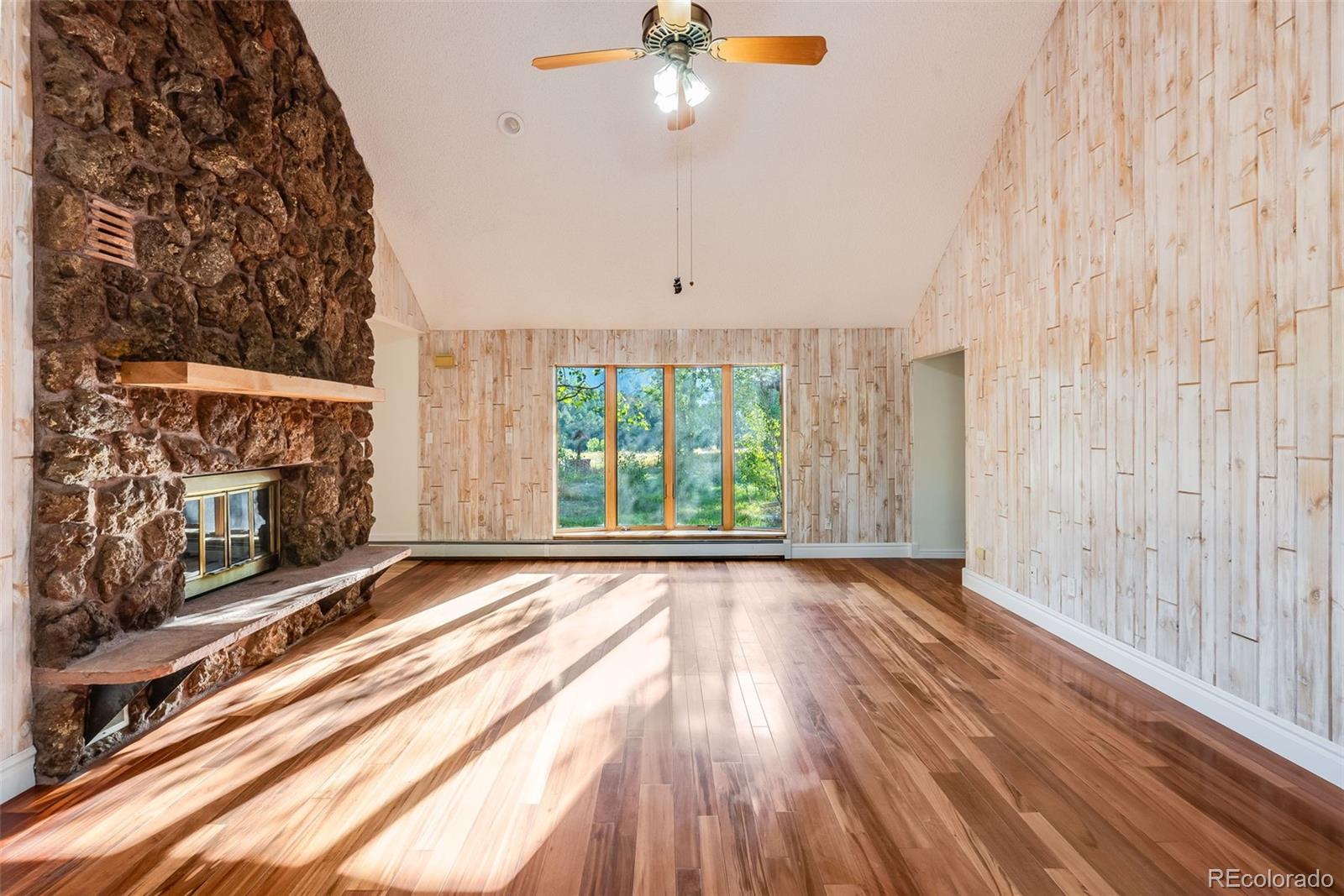 7572 Surrey Drive Morrison, CO 80465 - Photo 13 of 38 a view of an empty room with wooden floor fireplace and a window