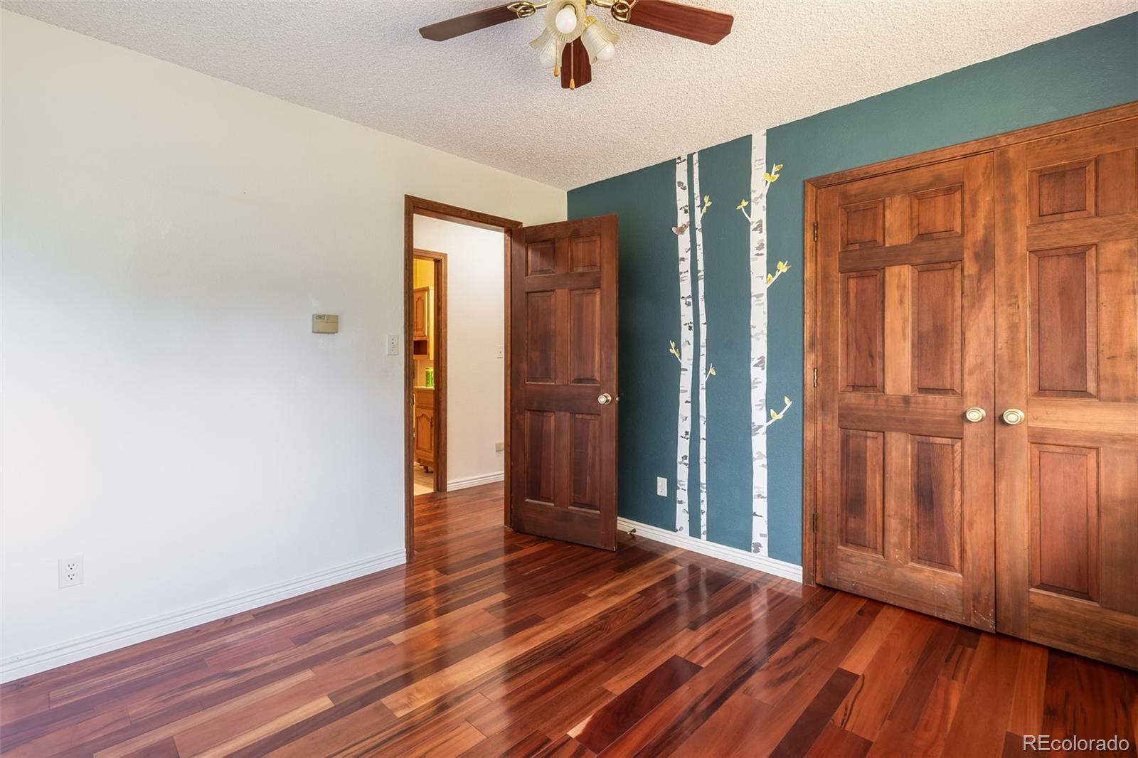 7572 Surrey Drive Morrison, CO 80465 - Photo 20 of 38 an empty room with wooden floor a ceiling fan
