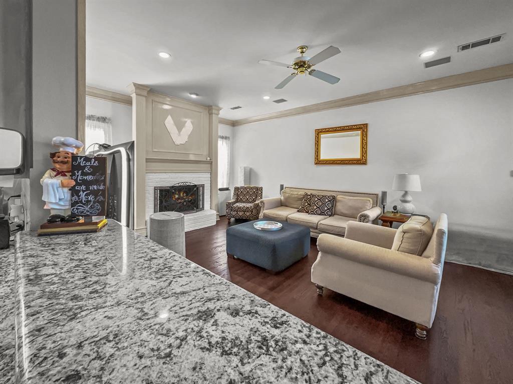 3405 Snidow Drive Plano, TX 75025 - Photo 13 of 24 Living room with ornamental molding, a ceiling fan, dark wood-style flooring, and a brick fireplace