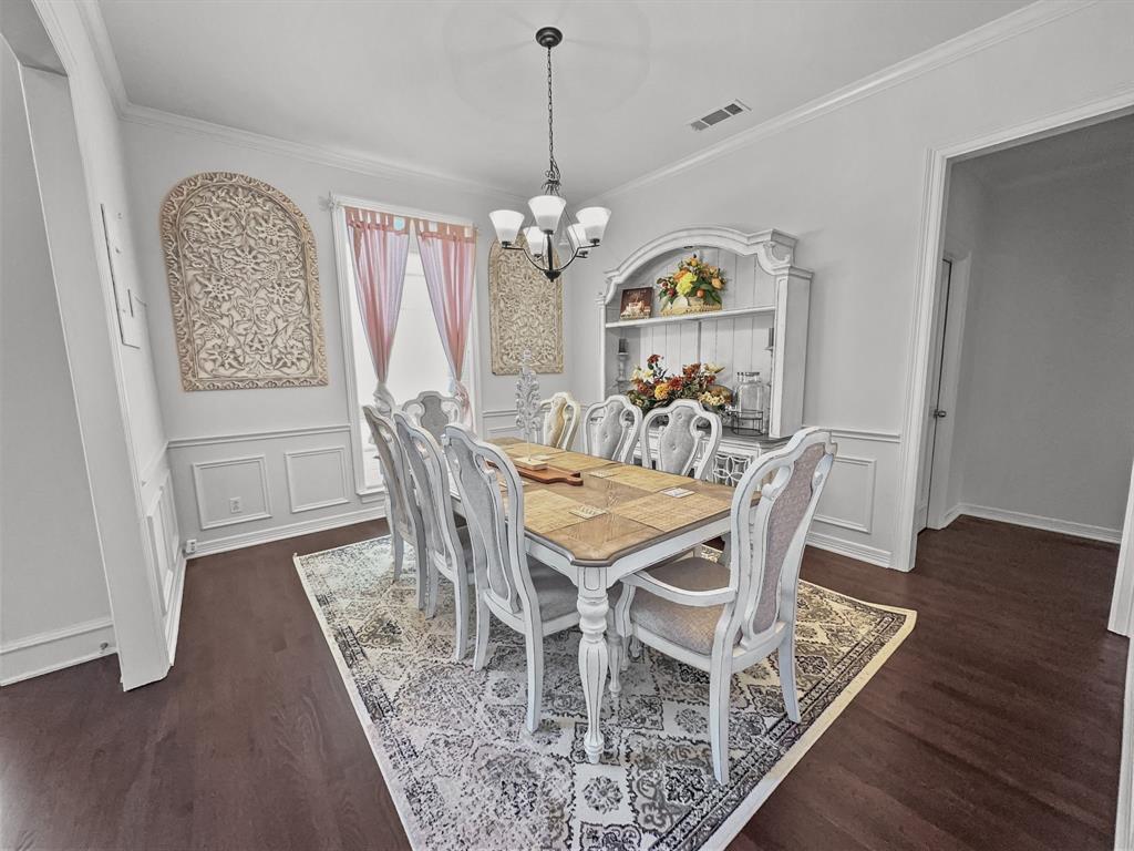 3405 Snidow Drive Plano, TX 75025 - Photo 8 of 24 Dining space with a chandelier, wood finished floors, crown molding, a wainscoted wall, and a decorative wall