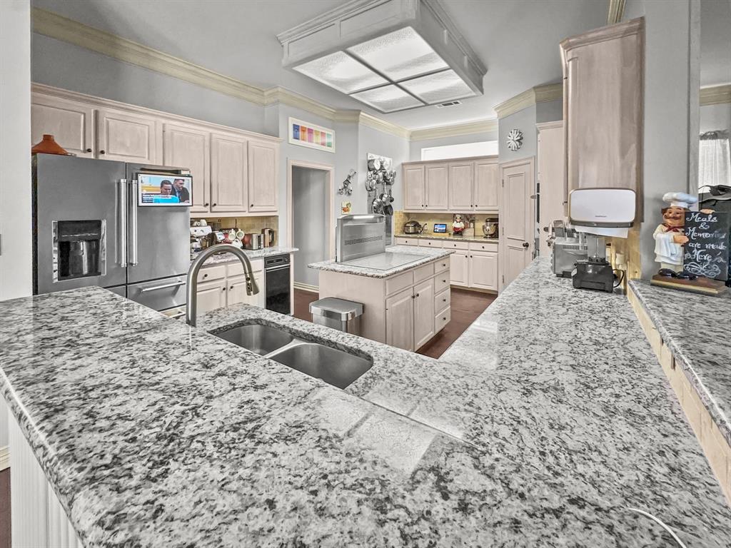 3405 Snidow Drive Plano, TX 75025 - Photo 10 of 24 Kitchen featuring high end refrigerator, ornamental molding, light stone countertops, a center island, and decorative backsplash