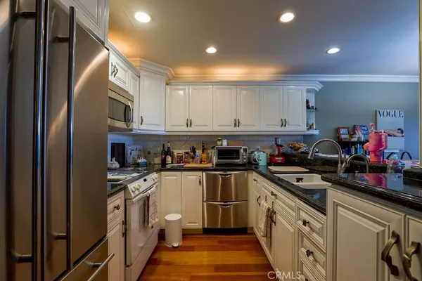 a kitchen with stainless steel appliances a sink dishwasher stove refrigerator and cabinets with wooden floor