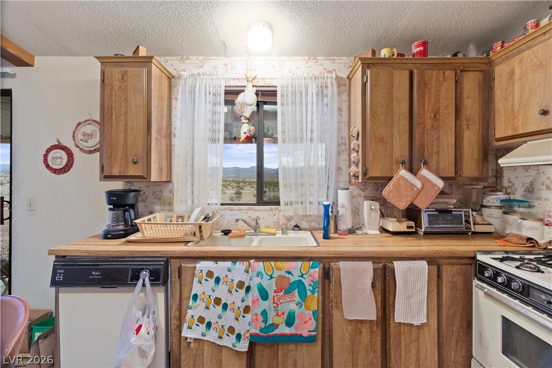 1609 Cajon Court Laughlin, NV 89029 - Photo 8 of 69 Kitchen with white appliances, wood finish cabinets, a textured ceiling, and wallpapered walls